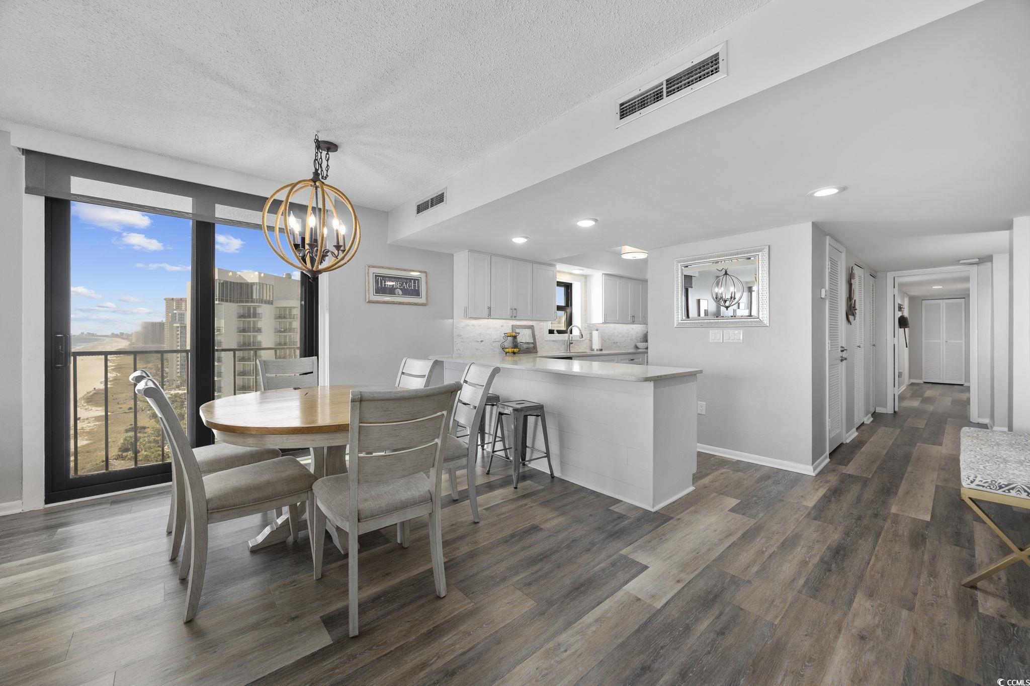 10100 Beach Club Drive, Unit 14F Myrtle Beach, SC 29572 - Photo 14 of 40 Dining room with a chandelier, dark wood-type flooring, and a textured ceiling
