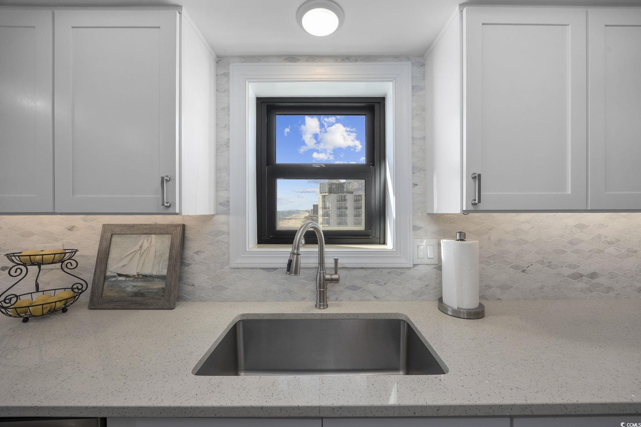 10100 Beach Club Drive, Unit 14F Myrtle Beach, SC 29572 - Photo 18 of 40 Kitchen featuring light stone counters, backsplash, and white cabinets