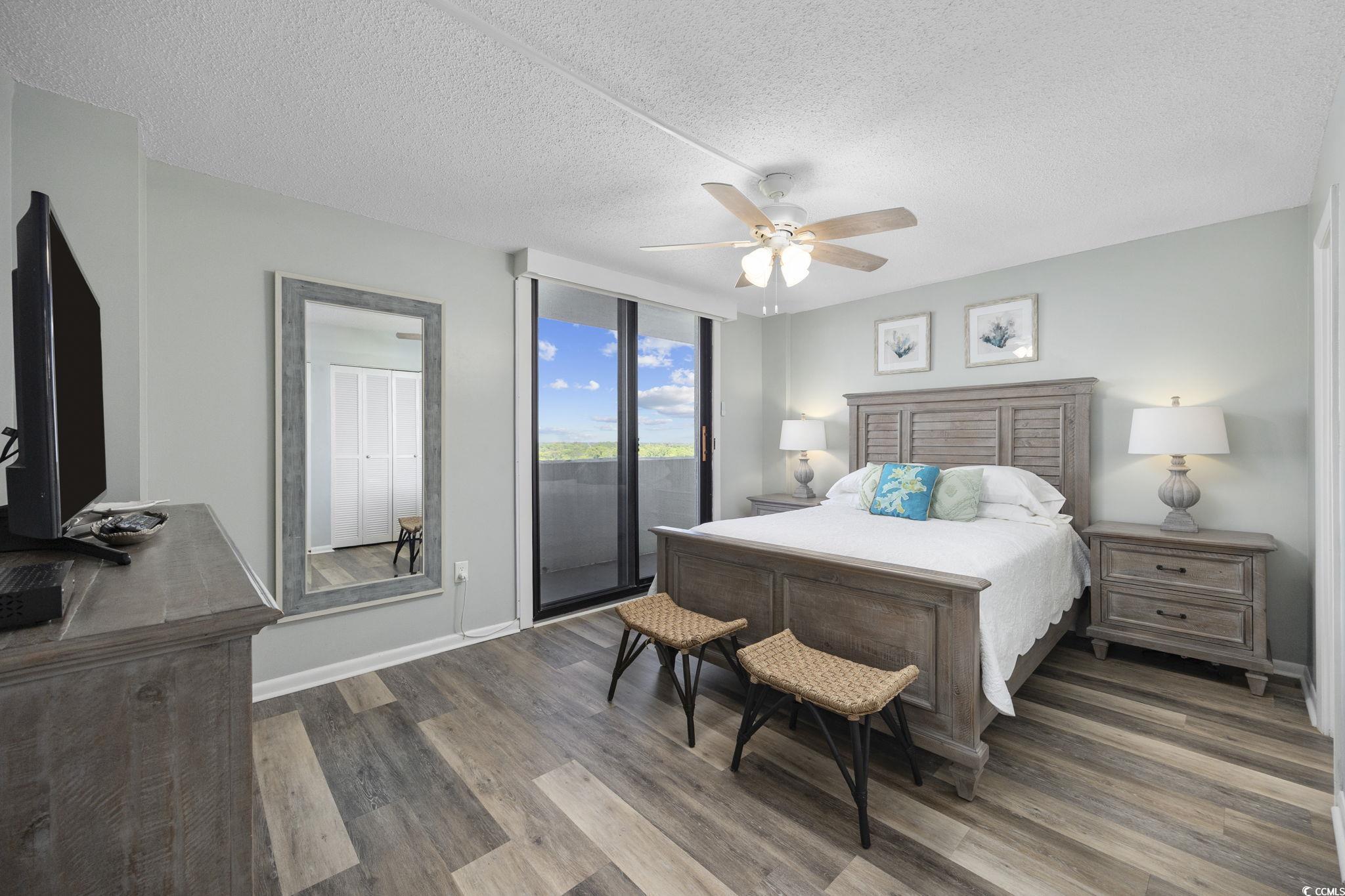 10100 Beach Club Drive, Unit 14F Myrtle Beach, SC 29572 - Photo 20 of 40 Bedroom with access to outside, dark wood-style floors, a textured ceiling, a ceiling fan, and a wall of windows