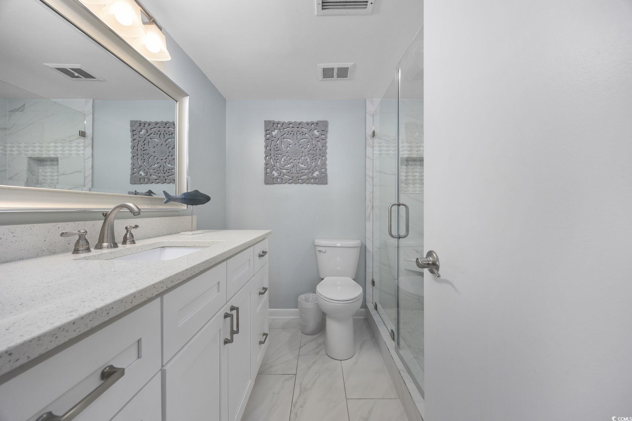 10100 Beach Club Drive, Unit 14F Myrtle Beach, SC 29572 - Photo 22 of 40 Bathroom featuring vanity, light marble finish floors, and a shower stall