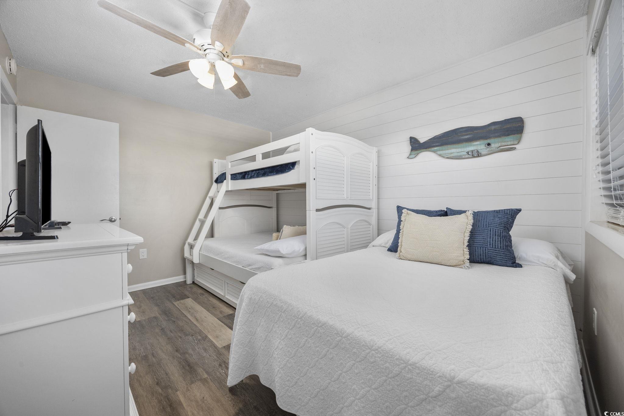 10100 Beach Club Drive, Unit 14F Myrtle Beach, SC 29572 - Photo 28 of 40 Bedroom with dark wood finished floors, a ceiling fan, and wood walls