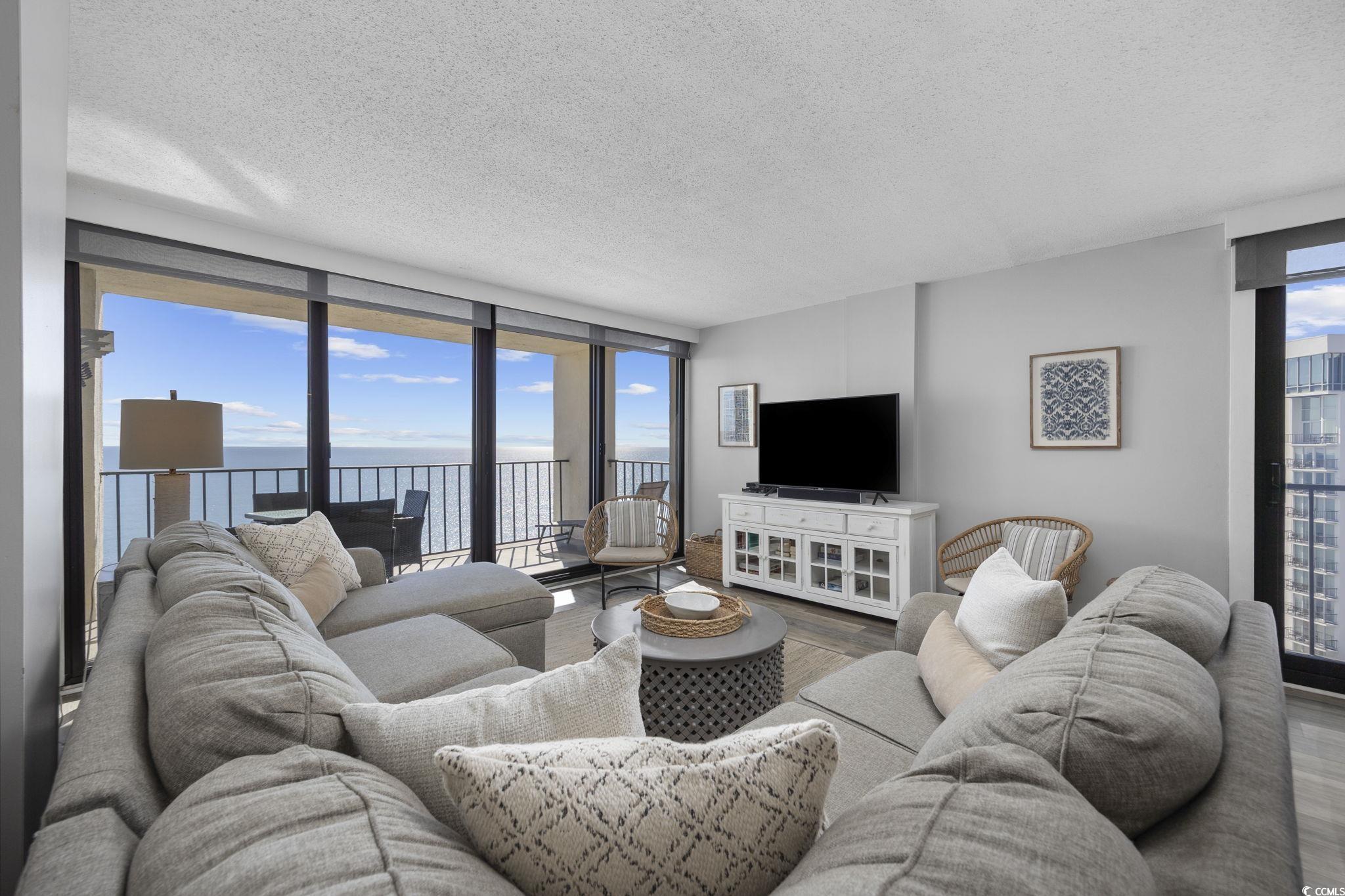 10100 Beach Club Drive, Unit 14F Myrtle Beach, SC 29572 - Photo 5 of 40 Living area featuring floor to ceiling windows, a textured ceiling, and wood finished floors