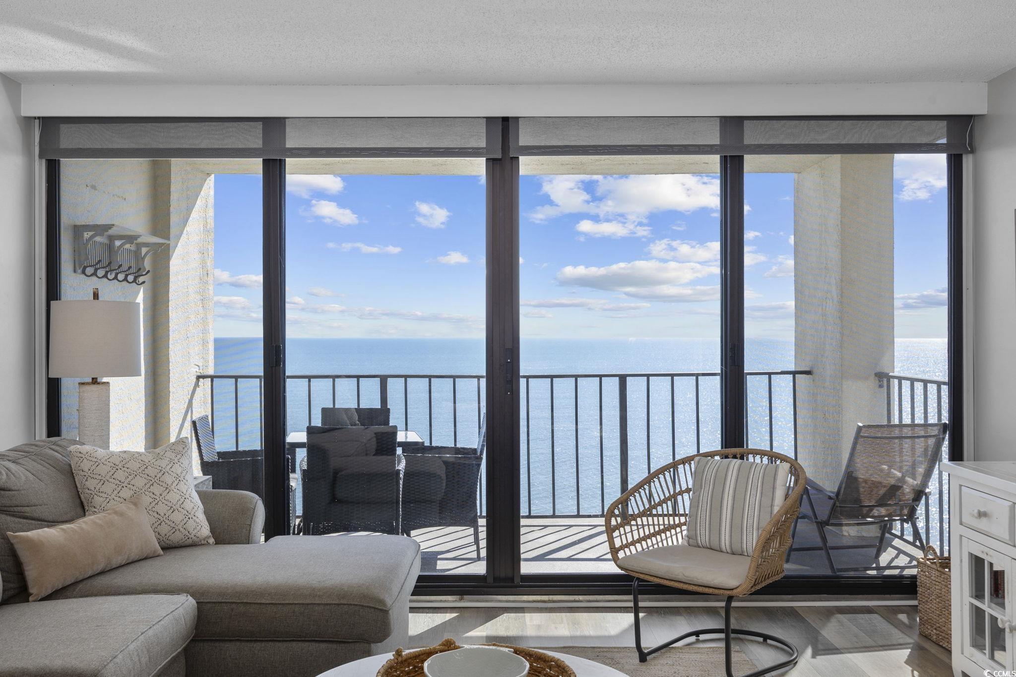 10100 Beach Club Drive, Unit 14F Myrtle Beach, SC 29572 - Photo 8 of 40 Living room featuring wood finished floors, a water view, healthy amount of natural light, a wall of windows, and a textured ceiling