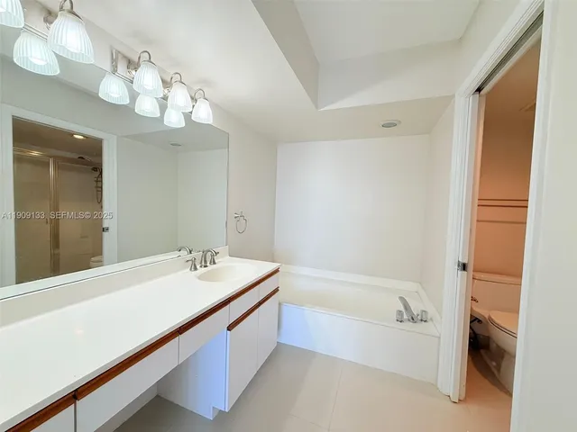 a bathroom with a tub a sink and a mirror