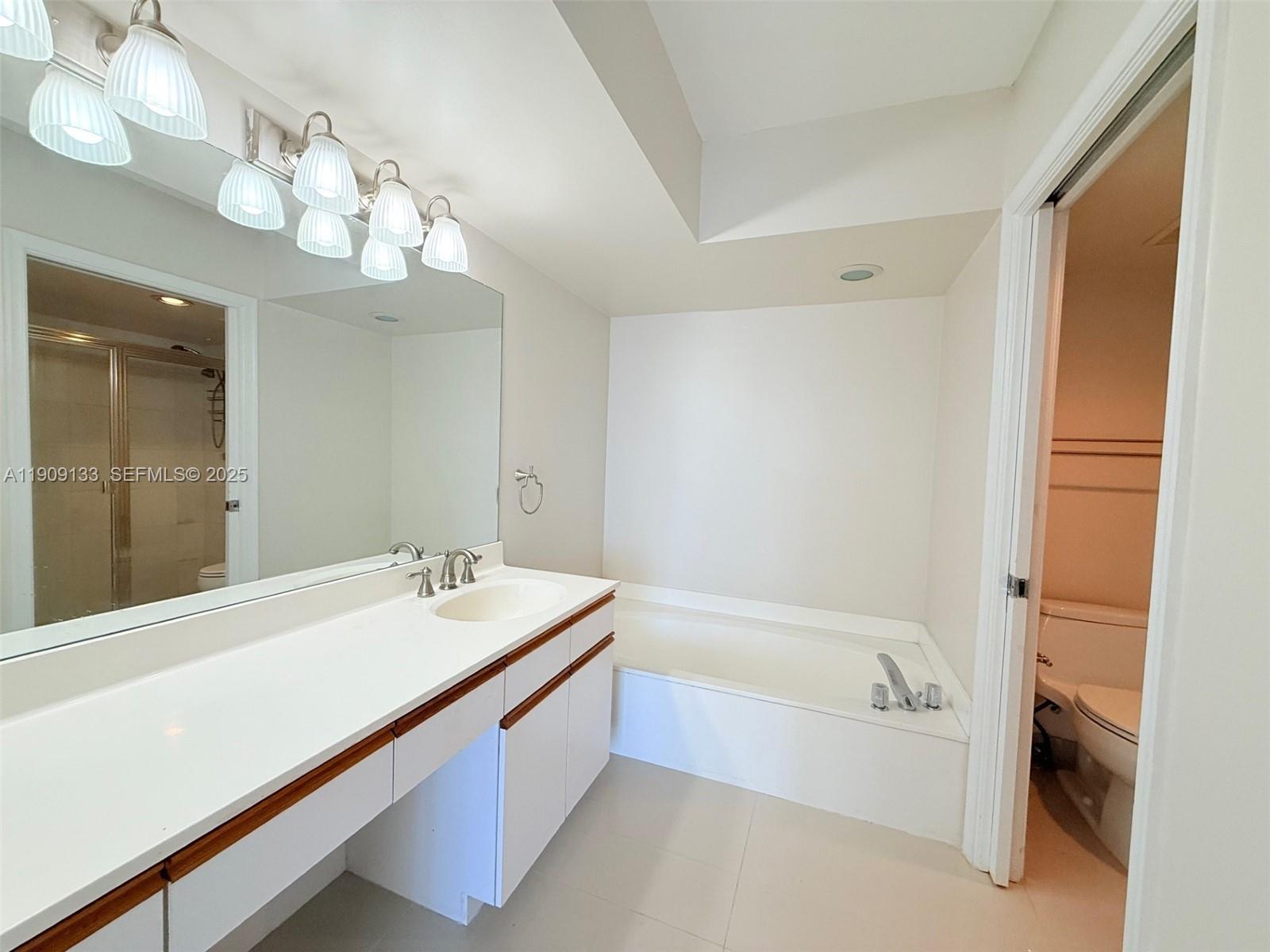 3530 Mystic Pointe Drive, Unit 1204 Aventura, FL 33180 - Photo 11 of 16 a bathroom with a tub a sink and a mirror