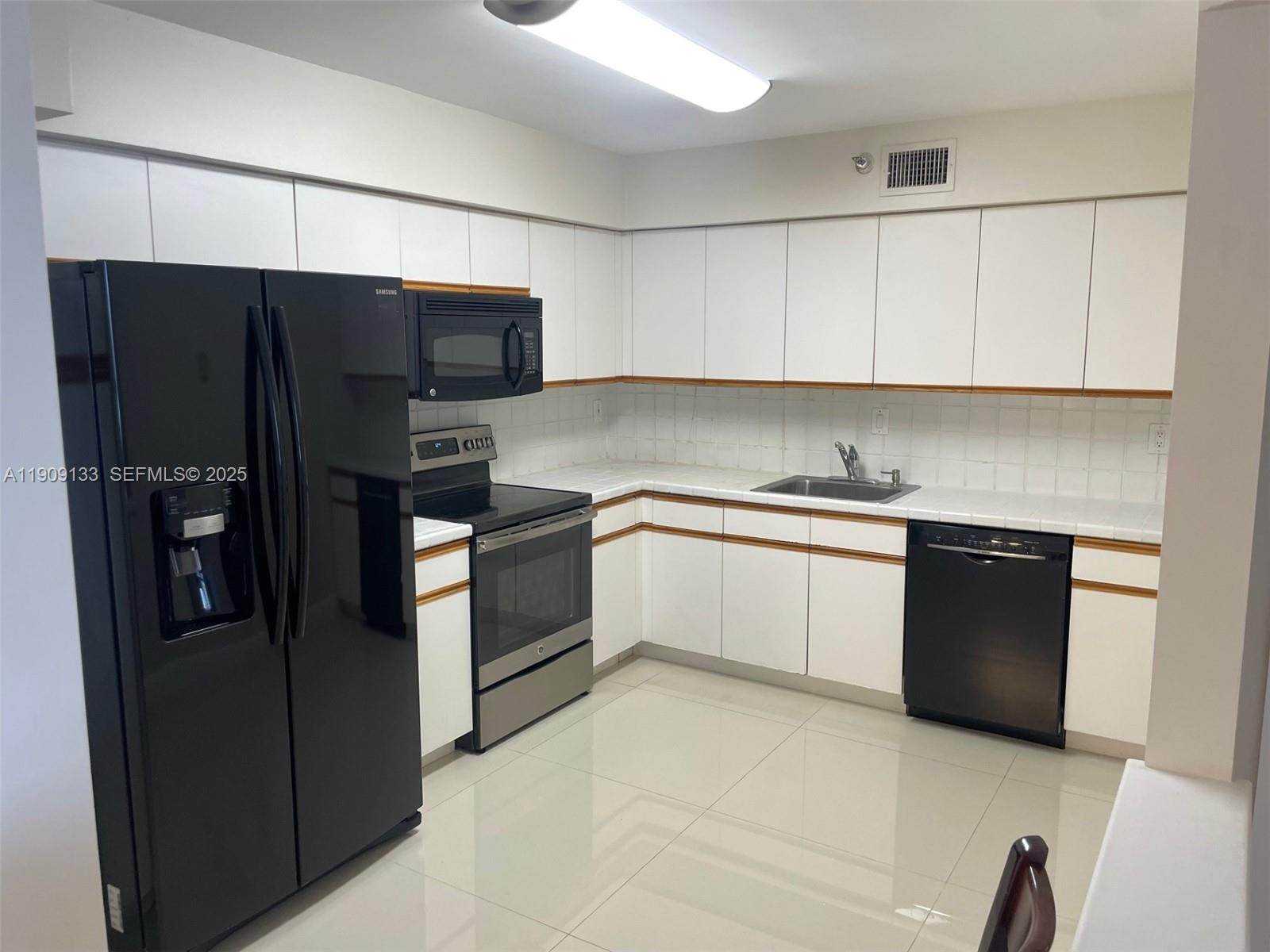 3530 Mystic Pointe Drive, Unit 1204 Aventura, FL 33180 - Photo 8 of 16 a kitchen with a refrigerator sink and cabinets