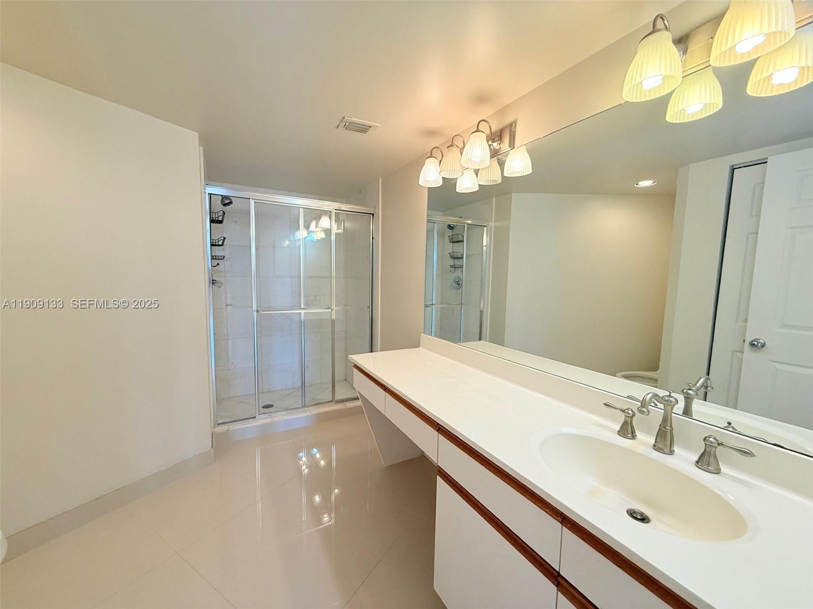 3530 Mystic Pointe Drive, Unit 1204 Aventura, FL 33180 - Photo 10 of 16 a bathroom with a sink a mirror and a shower