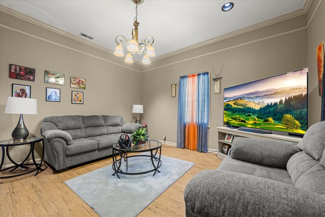 1102 West End Avenue Anderson, SC 29625 - Photo 6 of 28 The generously sized living room boasts crown molding and warm wood-look flooring.