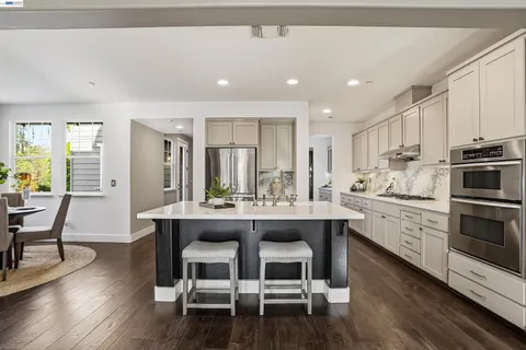 a kitchen with stainless steel appliances granite countertop a table chairs stove microwave and cabinets