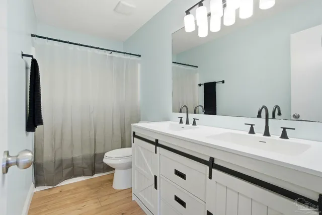 a bathroom with a sink a toilet a mirror and shower curtain