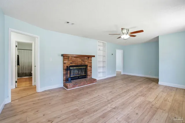 an empty room with wooden floor fireplace and a window