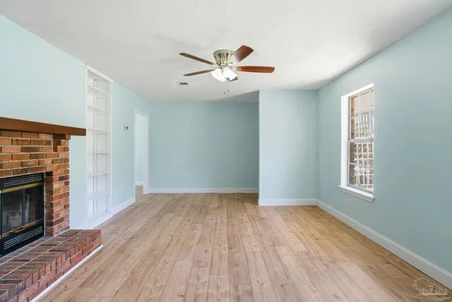 an empty room with windows and fireplace