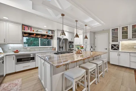 a kitchen with stainless steel appliances kitchen island granite countertop a stove and a white cabinets