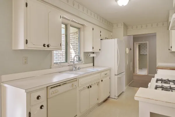 a kitchen with a sink and white cabinets next to a window