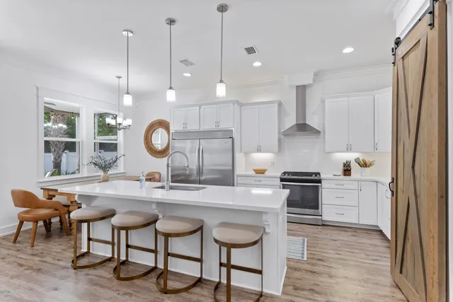 a kitchen with stainless steel appliances granite countertop a stove a sink a oven a dining table and chairs with wooden floor