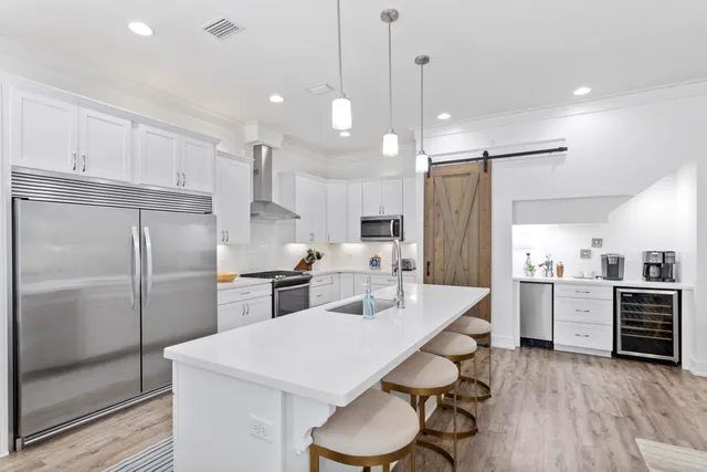 a kitchen with stainless steel appliances kitchen island granite countertop a refrigerator a sink dishwasher a stove and white cabinets with wooden floor
