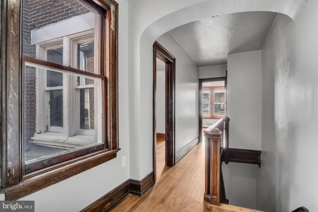 an empty room with wooden floor chandelier fan and windows