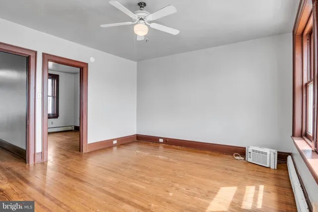 a view of empty room with wooden floor and fan