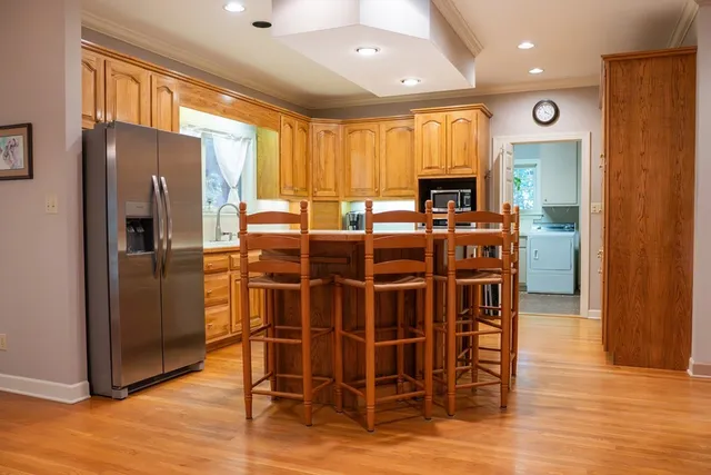 a kitchen with stainless steel appliances kitchen island granite countertop a refrigerator a stove a microwave oven with a dining table and chairs
