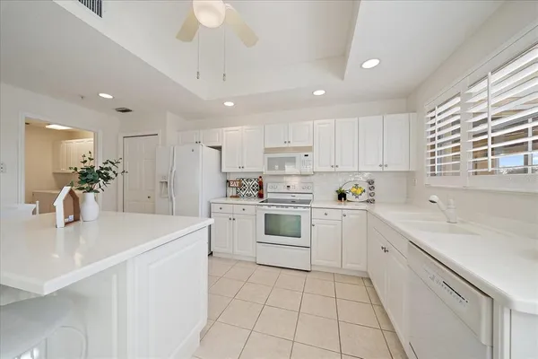 a kitchen with a sink white cabinets and white appliances