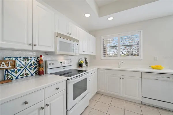 a kitchen with granite countertop white cabinets white stainless steel appliances and sink