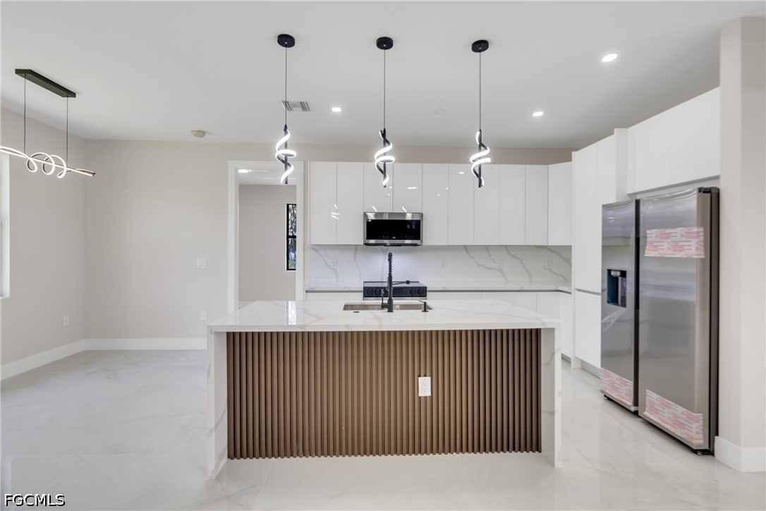 507 Trinity Street East Lehigh Acres, FL 33974 - Photo 20 of 50 a kitchen with kitchen island a sink stainless steel appliances and a counter top space