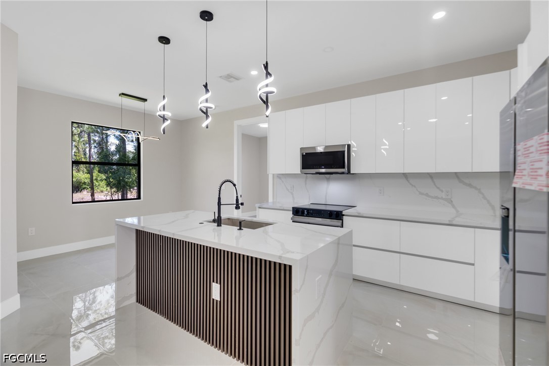 507 Trinity Street East Lehigh Acres, FL 33974 - Photo 21 of 50 a kitchen with stainless steel appliances kitchen island a sink dishwasher a stove and a microwave oven