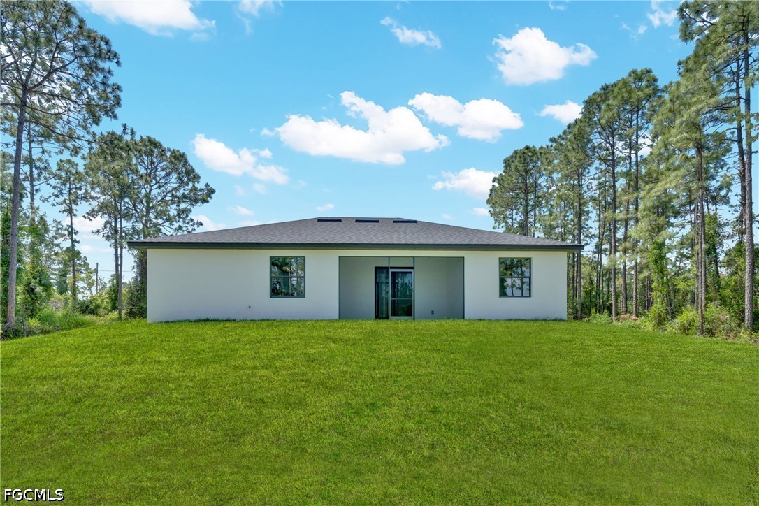 507 Trinity Street East Lehigh Acres, FL 33974 - Photo 44 of 50 a house that is sitting in the grass with tress in the background