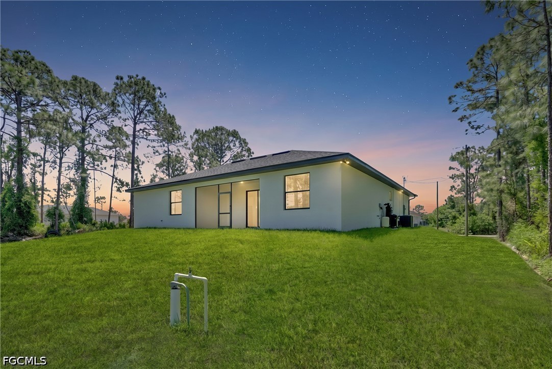 507 Trinity Street East Lehigh Acres, FL 33974 - Photo 46 of 50 a house that is sitting in the grass with large trees and plants
