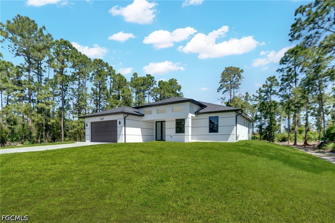 507 Trinity Street East Lehigh Acres, FL 33974 - Photo 8 of 50 a white house with a big yard and large trees
