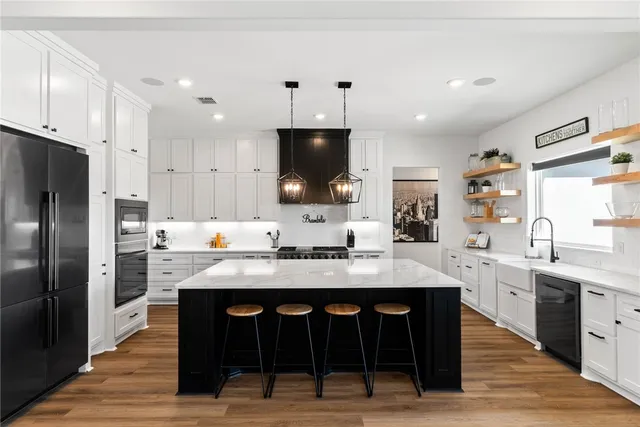 a large kitchen with stainless steel appliances kitchen island granite countertop a table chairs sink and cabinets