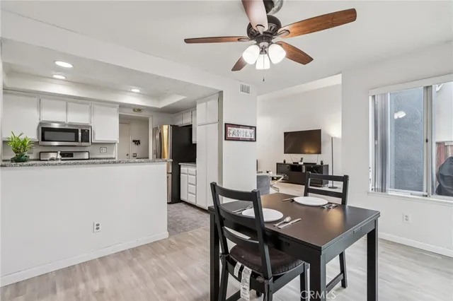a kitchen with stainless steel appliances kitchen island granite countertop a stove a sink a refrigerator a dining table and chairs with wooden floor