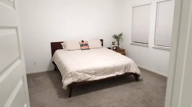 a bed sitting in a spacious bedroom next to a window