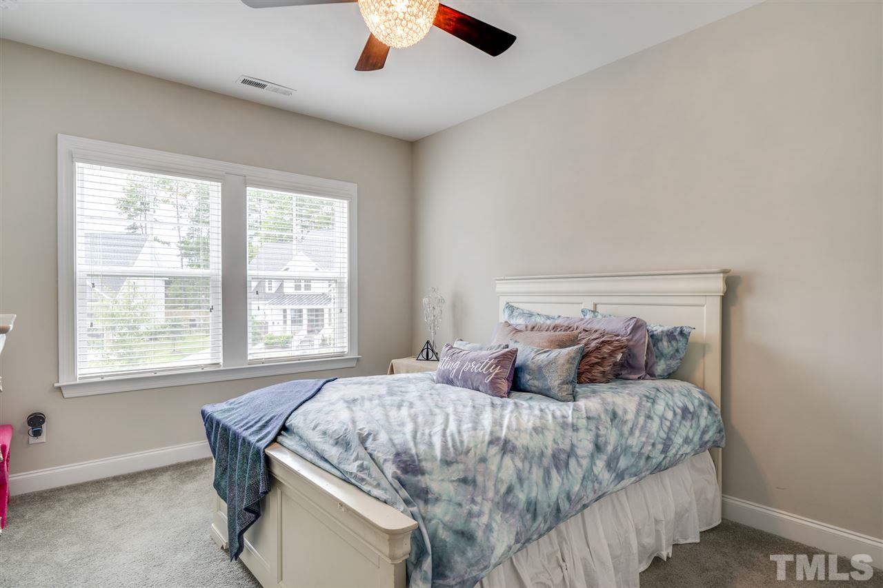 7504 Pinaster Place Raleigh, NC 27613 - Photo 21 of 30 a bedroom with a large bed and a chandelier