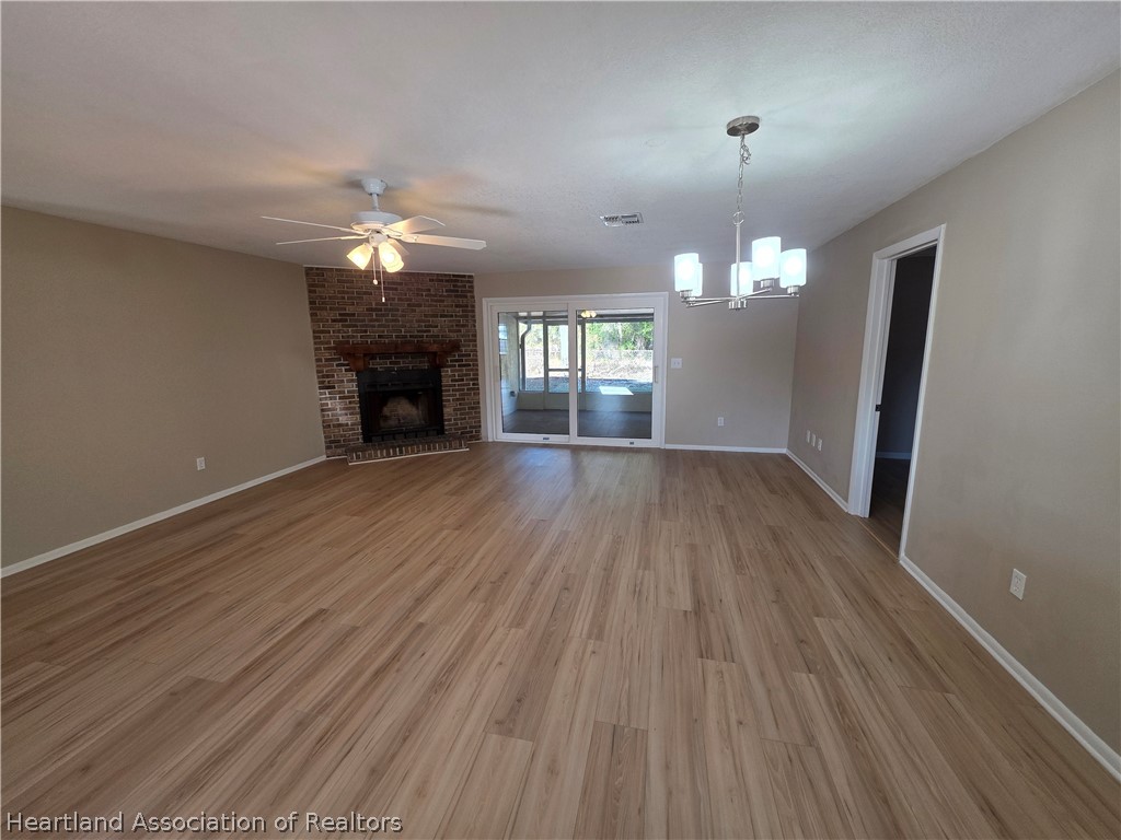 2858 North Lancaster Road Avon Park, FL 33825 - Photo 5 of 13 an empty room with wooden floor fireplace and chandelier fans