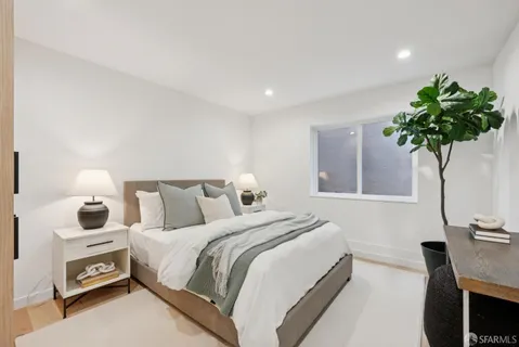 a bedroom with bed and a potted plant with wooden floor