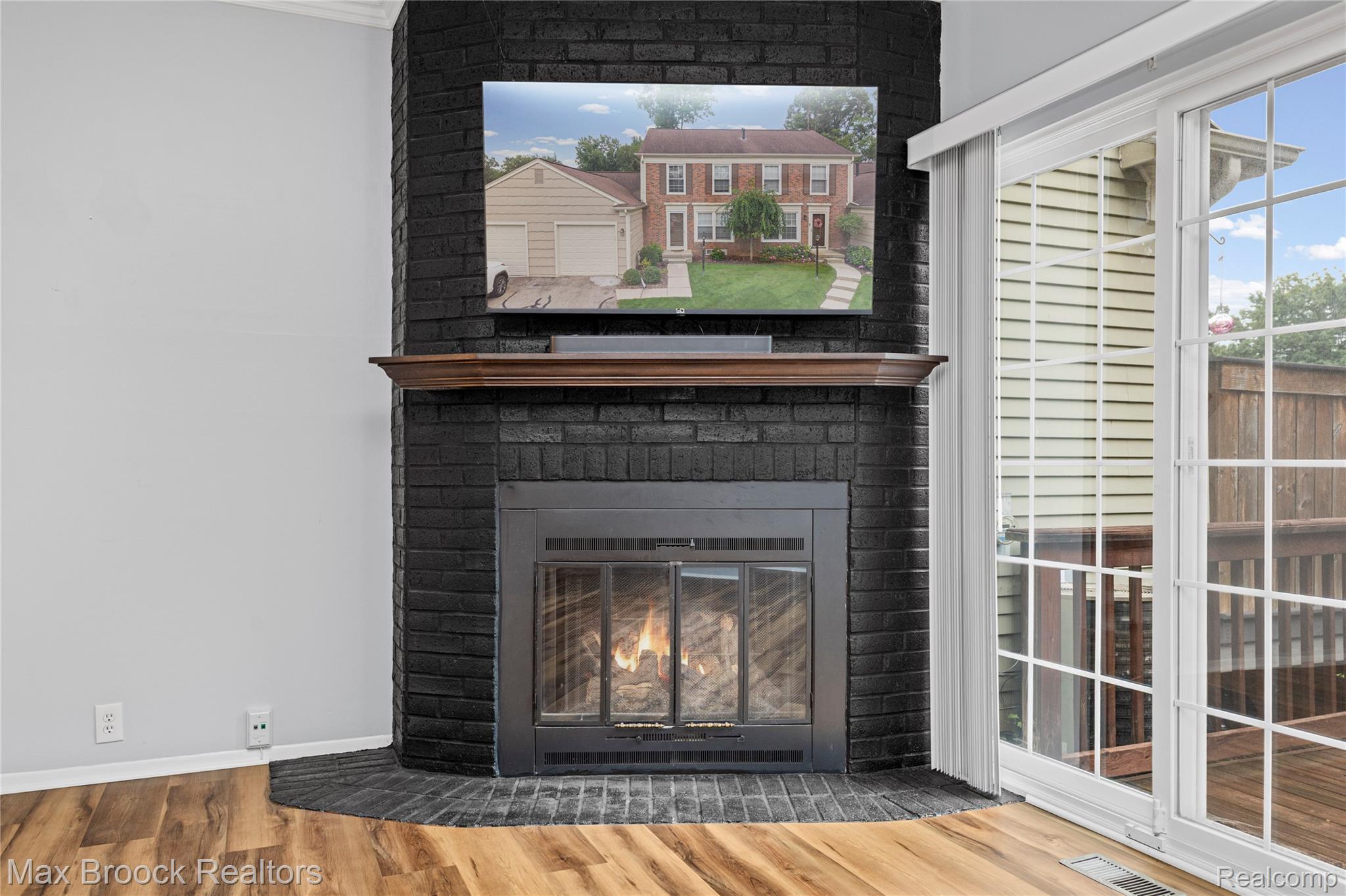 1157 Pine Ridge Court Rochester, MI 48306 - Photo 16 of 55 Contemporary fireplace anchors this light-filled room, featuring a black brick surround with glass doors, wood mantel, and mounted flat-screen television