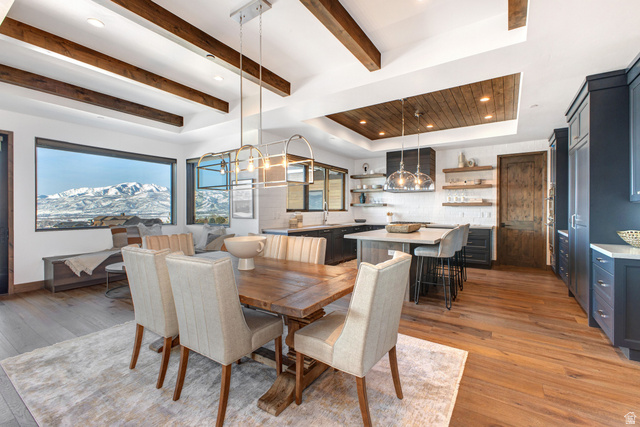 1282 Chimney Rock Road, Unit 344 Heber City, UT 84032 - Photo 12 of 55 Open-concept dining and kitchen area featuring a large window with mountain scenery, exposed ceiling beams, wood-finish flooring, a kitchen island with seating, and dark cabinetry