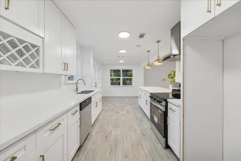 a kitchen with white cabinets and wooden floor