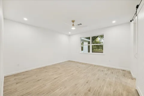 an empty room with wooden floor ceiling fan and windows