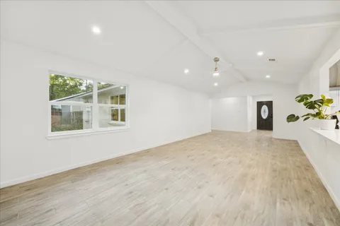 a view of an empty room with a window and wooden floor