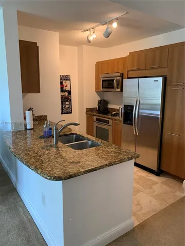 a kitchen with stainless steel appliances granite countertop a sink refrigerator and microwave