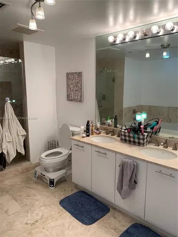 a spacious bathroom with a double vanity sink a toilet and a mirror