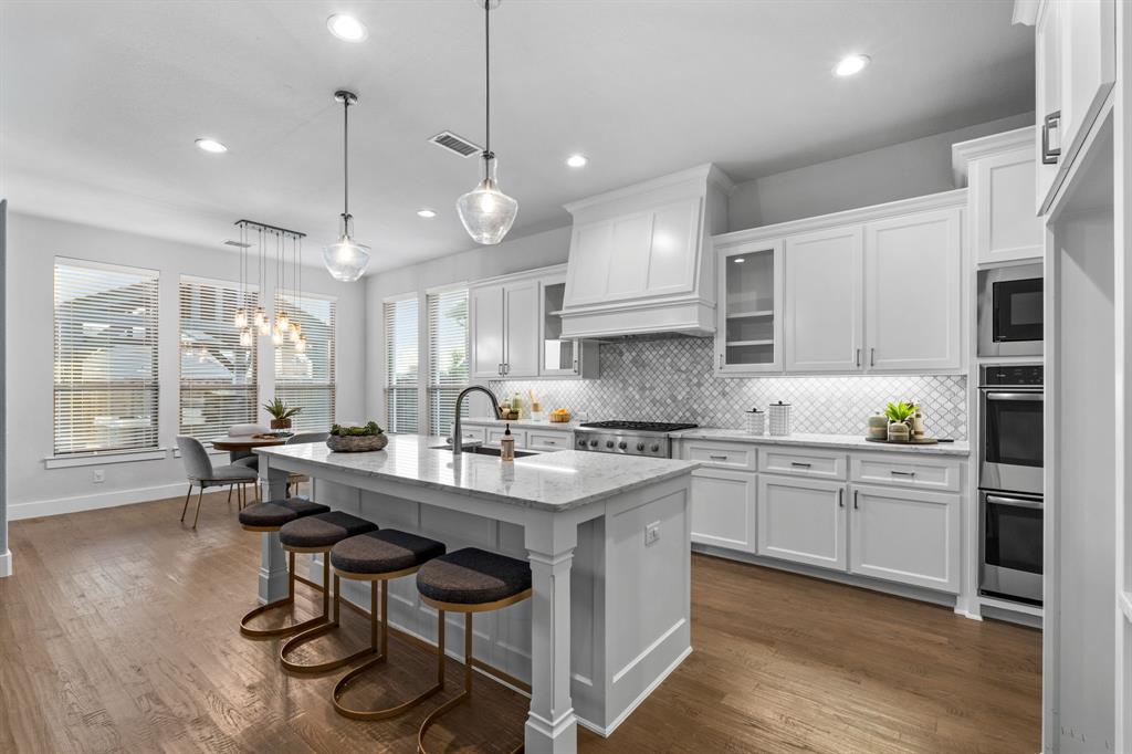 4003 Marble Hill Road Frisco, TX 75034 - Photo 11 of 40 a kitchen with stainless steel appliances granite countertop a stove a sink dishwasher a refrigerator and white cabinets with wooden floor