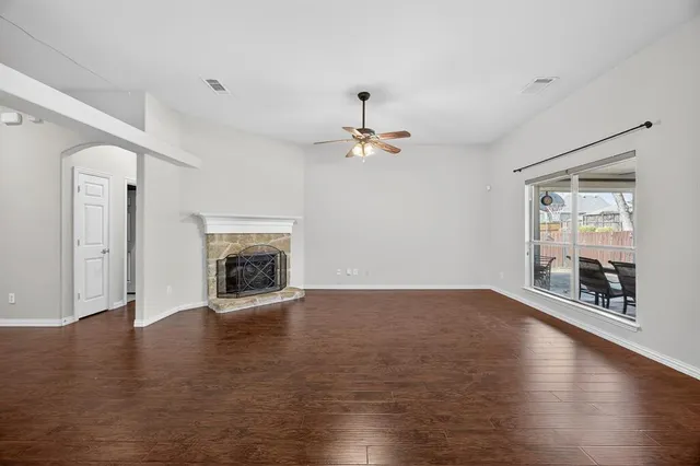 an empty room with wooden floor fireplace and windows