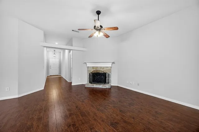 a view of an empty room with wooden floor fireplace and a window