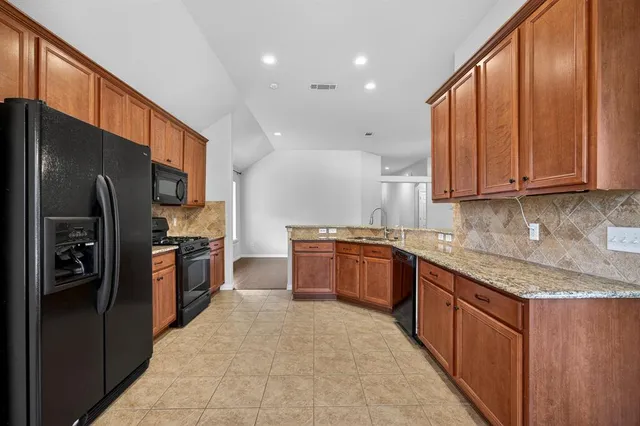 a large kitchen with stainless steel appliances granite countertop a refrigerator a sink and a stove