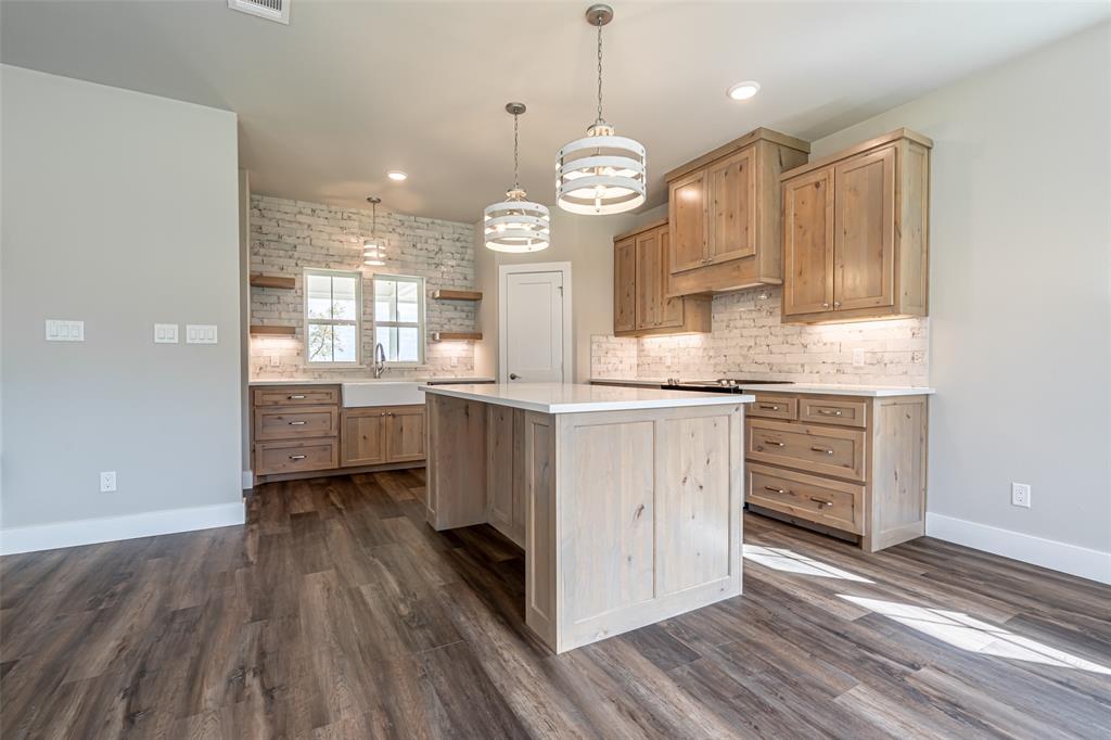 2044 Salina Circle Granbury, TX 76048 - Photo 15 of 38 a kitchen with stainless steel appliances a stove a sink and white cabinets with wooden floor
