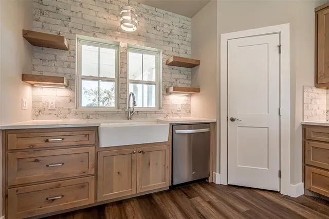 a kitchen with stainless steel appliances a stove a sink and white cabinets with wooden floor