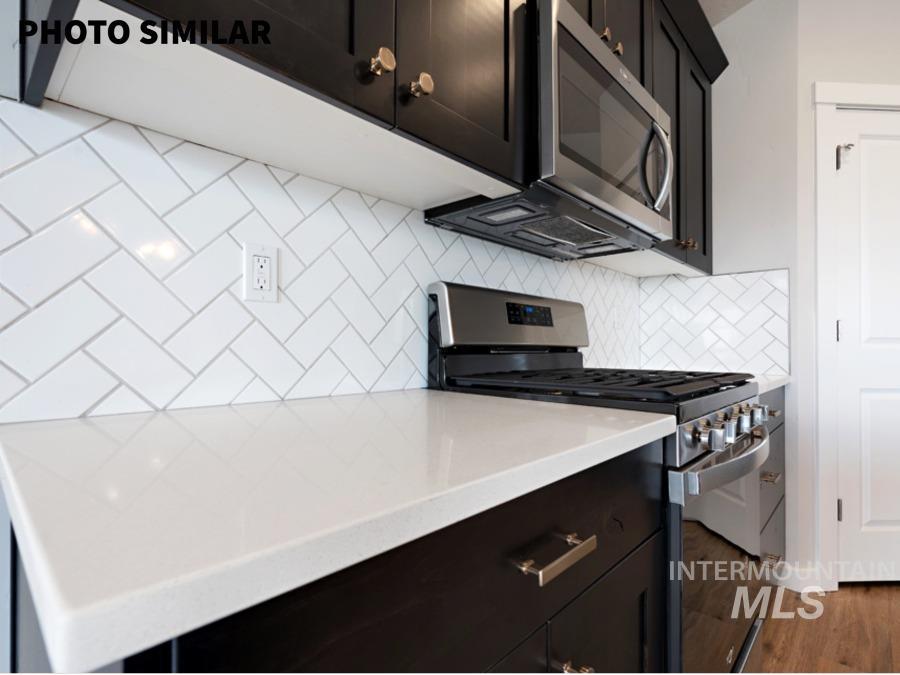 925 Twilight Weiser, ID 83672 - Photo 11 of 31 Kitchen featuring dark cabinetry with gold-toned hardware, stainless steel appliances, white herringbone tile backsplash, and light-toned countertops